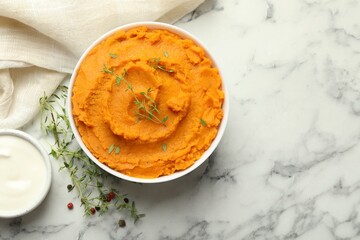Delicious mashed sweet potatoes in bowl, microgreens, sour cream and spices on white marble table, top view. Space for text