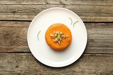 Plate with tasty mashed sweet potato, rosemary and walnuts on wooden table, top view
