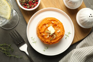 Tasty mashed sweet potato, butter, thyme and walnuts served on grey textured table, flat lay