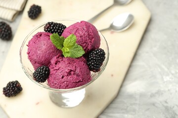 Delicious blackberry sorbet, fresh berries and mint in glass dessert bowl on gray textured table, closeup
