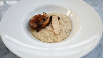 Elegant Plated Chicken with Mushroom and Creamy Risotto Dish on Marble Table in a Fine Dining Setting