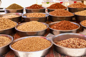 Many different nuts in large metal vices on the counter of a local bazaar