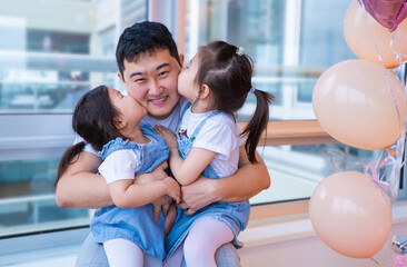 man is holding two young girls, one of whom is kissing the other