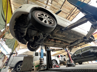 A car is lifted on a hydraulic lift in a garage, showcasing its undercarriage. The scene conveys a sense of maintenance and care for vehicles.