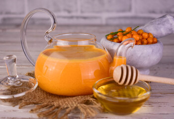 Tea from sea buckthorn berries in a transparent teapot.
