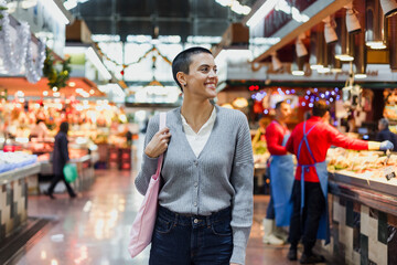 hispanic young woman with skinhead or short hair shopping vegetables and fruits on traditional market or grocery	