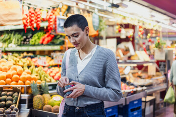 hispanic young woman with skinhead or short hair shopping vegetables and fruits on traditional market or grocery	
