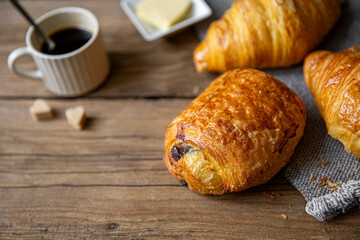 Pain au chocolat ou chocolatine sur le plateau en bois d'un petit déjeuner.