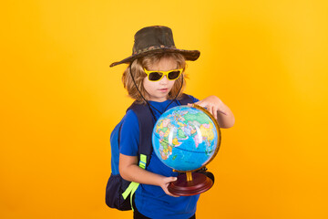 Child tourists with backpacks and camera hold world globe isolated on yellow background. Adventure, travel, and tourism concept. Little explorer on trip.