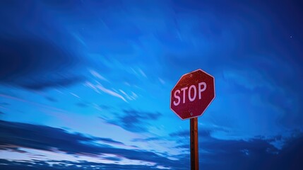 Long exposure shot of a still stop sign against the vivid blue sky