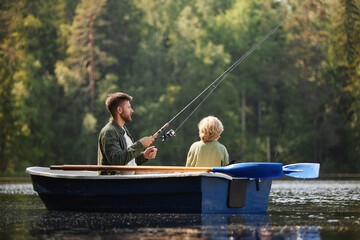 Two people sitting in boat surrounded by lush forest and calm water holding fishing rods on relaxing day fishing on peaceful lake creating bonding moment