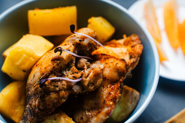 Close-up.Chicken fried with rustic potatoes in a blue bowl with tomatoes on a plate, napkin and fork, knife.