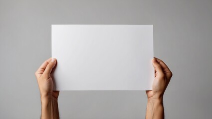 Fototapeta premium Hands holding a blank white sheet of paper against a neutral backdrop