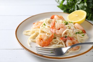 Delicious pasta with shrimps, green onion and fork on white wooden table, closeup