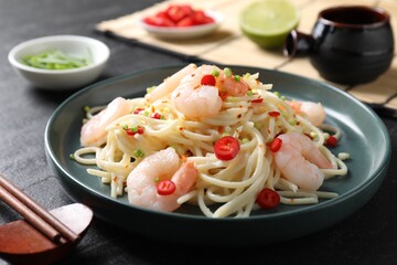 Delicious pasta with shrimps served on black table, closeup