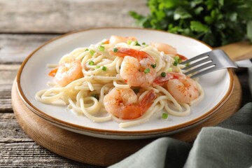 Delicious pasta with shrimps and green onions on wooden table, closeup