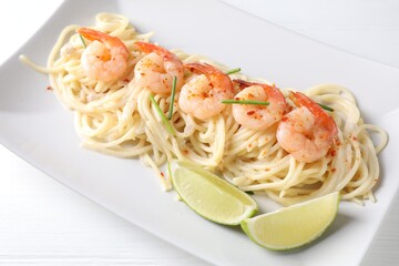 Delicious pasta with shrimps and lime on white wooden table, closeup
