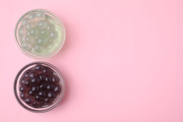 Color tapioca pearls in bowls on pink background, flat lay. Space for text