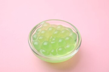 Bright tapioca pearls in bowl on pink background, closeup