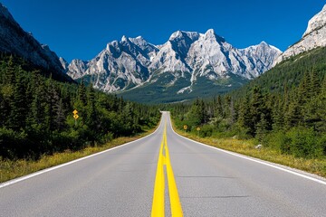 Fototapeta premium A straight road leading towards towering mountains, with green trees lining the sides. The bright blue sky adds a sense of openness and adventure.