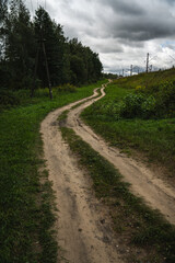 A rural, dirt road leading up. Cloudy sky