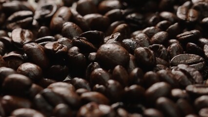 Macro shot of super slow motion shot of fresh coffee bean placed with black background. Close up of piles of aromatic roasted coffee seed surrounded. Macrography. Beans scattering around. Comestible.