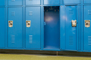 Single open empty blue metal locker along a nondescript hallway in a typical US High School. No identifiable information included and nobody in the hall.	