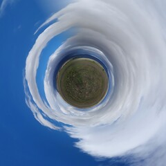 Little planet transformation of spherical panorama 360 degrees. Spherical abstract aerial view in blue sky with white clouds. Curvature of space.
