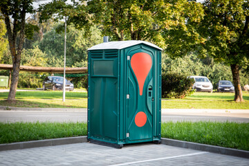 Green mobile toilet in the car parking outdoors, a temporary solution