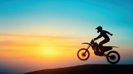 Obraz premium A silhouette of a motocross rider performing a jump against a vibrant sunset backdrop, showcasing adventure and excitement.