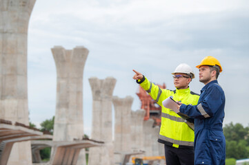 An Asian male engineer works at a motorway bridge construction site,Civil worker inspecting work on crossing construction,Supervisor working at high-speed railway construction site