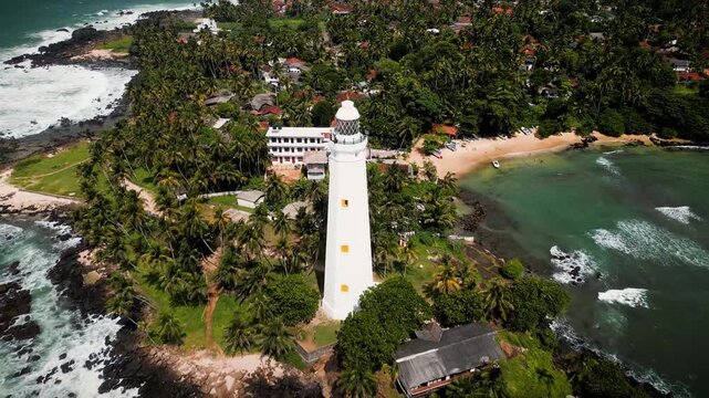 Reveal shot of Point Dondra Lighthouse in Sri Lanka, highlighting the stunning transition from coastal landscape to the iconic structure