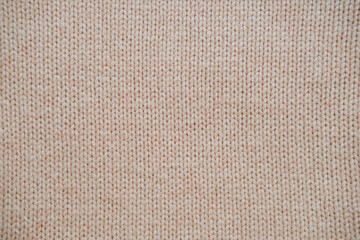 Close-up of the texture of knitted woolen fabric in light brown color