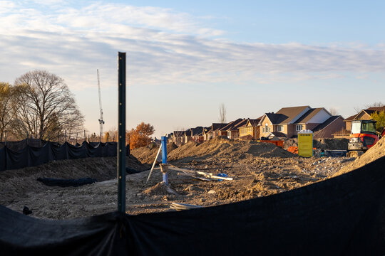 Golden hour at a suburban construction site - earth mounds and building materials foreground. Taken in Toronto, Canada.