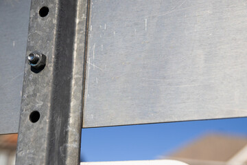 Rear view of a metal street sign showing bolted connections and weathered surface - clear blue sky...
