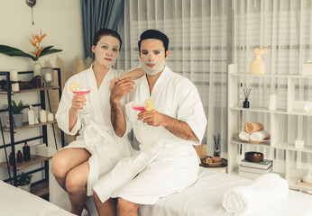 Serene modern daylight ambiance of spa salon, couple customer indulges in rejuvenating with facial skincare mask. Facial skin treatment and beauty cosmetology procedure for face. Quiescent