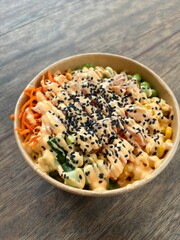 Poke bowl on wooden table with shallow background Too vie
