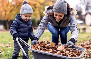 A mother and son picking up leaves into a wheelbarrow during fall.