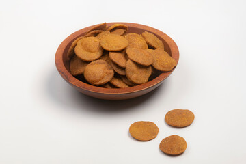 Studio shot of Indian Gujarati tea time snack Bajri Vada in a carved wooden bowl, isolated on white
