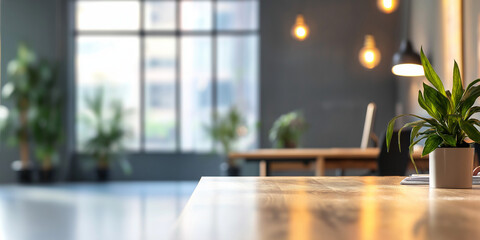 Modern office desk with laptop and plant, blurred background with large windows and pendant lights for professional workspace concept