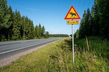 Finnish Road in Summer with Moose Warning Sign Surrounded by Trees