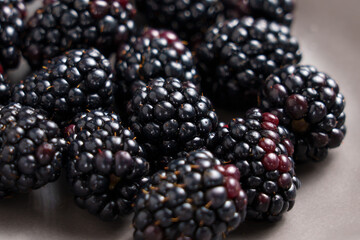 Fresh blackberry with rich hue and plump form in grey plate. Healthy smoothie ingredients