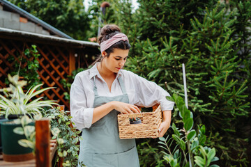 Young woman taking care of plants with water can and mister in garden