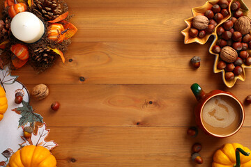 Top view Autumn background with pumpkins, leaf shaped plate with nuts, acorns, candle with pine cones, cloth on wooden table. Autumn holiday, fall concept.