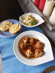 Spanische Hackbällchen mit Tomatensoße, Salat und Brot mit Kräuterbutter