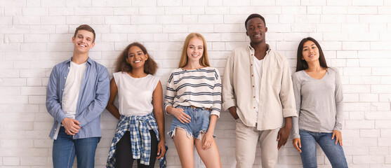 Carefree group of international students hipsters posing over white wall, youth culture concept