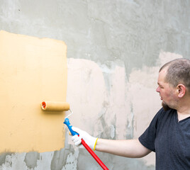 A man is painting a wall with a roller