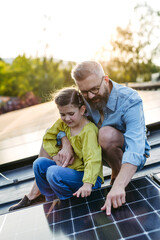 Dad and girl on roof with solar panels, learning about solar energy. Rooftop solar or photovoltaic...