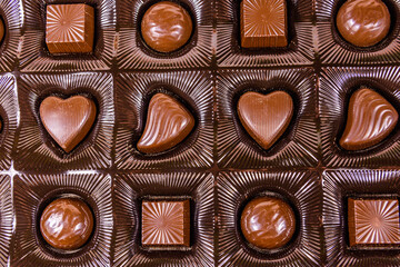 Heap of chocolate candies in a brown box. Top view