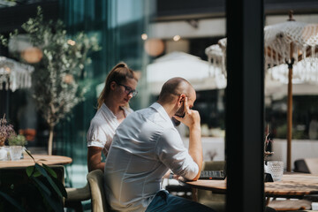 Business workers collaborating on a project in a coffee bar, brainstorming ideas, and sharing knowledge while working remotely in a relaxed environment.